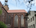 Zdjęcie przedstawia fragment kościoła, który wchodzi w skład dawnego klasztoru cystersów w Kołbaczu. Na pierwszym planie widać dwa okna kościoła. Z lewej strony widoczny jest budynek plebani.         
