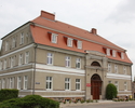 Zdjęcie przedstawia dawną siedzibę domeny w Kołbaczu. Na pierwszym planie widoczna jest lewa część frontowej elewacji oraz fragment bocznej ściany budynku.                                             