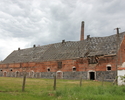 Zdjęcie przedstawia dawny folwark w Witnicy. Na pierwszym planie widać jeden z budynków gospodarczych. Obiekt jest w ruinie.                                                                            