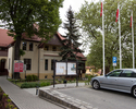 Zdjęcie przedstawia urząd gminy w Widuchowej. Na pierwszym planie widoczny jest parking mieszczący się przed urzędem, dalej, wśród drzew widać gmach urzędu.                                            