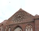 Zdjęcia przedstawia kościół, który wchodzi w skład dawnego zespołu klasztornego w Kołbaczu. Na pierwszym planie widać ozdobną rozetę, która mieści się na szczycie tylnej elewacji zabytku.             