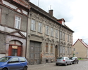 Zdjęcie przedstawia dom mieszkalny przy ul. Jana Pawła II 14 w Mieszkowicach. Na pierwszym planie widać frontową elewację z bramą wjazdową.                                                             