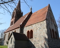 Zdjęcie przedstawia ścianę boczną oraz tył kościoła zbudowanego z kamienia oraz cegły.                                                                                                                  
