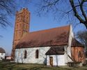 Zdjęcie przedstawia boczną ścianę oraz tył kościoła. Wieża wykonana z czerwonej cegły.                                                                                                                  