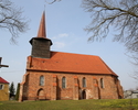 Zdjęcie przedstawia ścianę boczną kościoła usytuowanego na lekkim wzniesieniu.                                                                                                                          