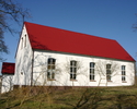 Zdjęcie przedstawia kościół od strony bocznej, który jest pokryty białym tynkiem.                                                                                                                       