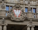 Zdjęcie przedstawia fragment gmachu Zachodniopomorskiego Urzędu Wojewódzkiego. Na pierwszym planie widać godło Polski, które znajduje się bezpośrednio nad głównym wejściem do budynku.                 