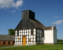 Zdjęcie przedstawia kościół od strony wejścia, którego konstrukcja jest drewniana.                                                                                                                      