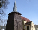Na zdjęciu znajduje się strona wejścia oraz ściana boczna kościoła, którego wieża ma konstrukcje drewnianą.                                                                                             