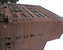 Zdjęcie przedstawia wysoki budynek z czerwonej cegły, należący do grupy obiektów fabryki papieru                                                                                                        