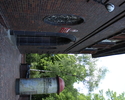 Zdjęcie przedstawia główne wejście do budynku oraz słup informacyjny przed nim.                                                                                                                         