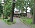 Zdjęcie przedstawia dawnym dom zdrojowy w Trzcińsku-Zdroju. Na pierwszym planie widać dwie aleje, w tle, pomiędzy drzewami dom pomocy społecznej.                                                       