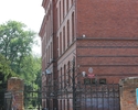 Zdjęcie przedstawia zespół budynków gimnazjum w Chojnie. Na pierwszym planie widać bramę, za nią fragment głównego budynku szkoły.                                                                      