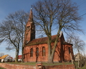 Na zdjęciu znajduje się ściana boczna oraz tył kościoła, który został zbudowany z cegły oraz położony jest na lekkim podwyższeniu.                                                                      