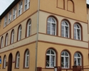 Zdjęcie przedstawia szkołę w Trzcińsku-Zdroju. Na pierwszym planie widać frontową i boczną elewację głównego skrzydła szkoły.                                                                           