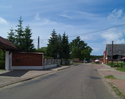 Zdjęcie przedstawia główną drogę we wsi Bobolin wraz z zabudowaniami.                                                                                                                                   