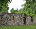 Zdjęcie przedstawia park w Lubiechowie Górnym. Na pierwszym planie widać ogrodzenie z kamienia, która otacza park.                                                                                      