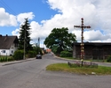 Zdjęcie przedstawiające zabudowę mieszkalną w Wicimicach wraz z krzyżem widzianymi z głównej drogi dojazdowej                                                                                           