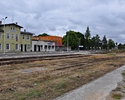 Zdjęcie przedstawia widok na tył budynku dworca kolejowego, peron oraz tory biegnące obok                                                                                                               