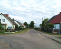 Zdjęcie przedstawia główną drogę we wsi Podgórki wraz z zabudowaniami.                                                                                                                                  