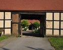 Zdjęcie przedstawia widok na wnętrze zagrody agroturystycznej w Gosławiu przez prowadzący do niej budynek bramny                                                                                        