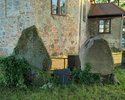 Zdjęcie przedstawia niewielkie lapidarium znajdujące się przy kościele pw. Podwyższenia Krzyża Św. w Ostrowcu.                                                                                          