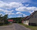 Zdjęcie przedstawia główną drogę we wsi Noskowo wraz z zabudowaniami.                                                                                                                                   