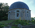 Zdjęcie przedstawia front kościoła w Gawrońcu wraz z ogrodem przykościelnym.                                                                                                                            
