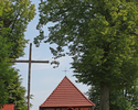 Zdjęcie przedstawia widok kościoła w Buślarach wkomponowanego w wysokie drzewa rosnące w ogrodzie przykościelnym.                                                                                       