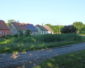 Zdjęcie przedstawia zabudowania wokół zarośniętego stawu w Dołganowie.                                                                                                                                  