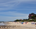 Zdjęcie przedstawia piaszczystą plażę, morze oraz wypoczywających turystów                                                                                                                              