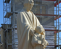 Zdjęcie przedstawia figurę Świętego Józefa na tle wieży kościoła PW Św JONMP w Połczynie-Zdroju.                                                                                                        