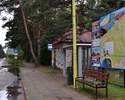 zdjęcie przedstawia przystanek autobusowy, drewnianą ławkę oraz tablicę informacyjną z mapą miejscowości                                                                                                
