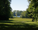 Zdjęcie przedstawia widok na jezioro z pałacu w Lekowie poprzez aleję parkową.                                                                                                                          
