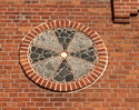 Zdjecie przedstawia krzyż słoneczny  umieszczony na ścianie plebani                                                                                                                                     