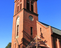 Zdjęcie przedstawia kościół z czerwonej cegły od frontu.                                                                                                                                                