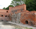 Na zdjęciu widać fragment murów obronnych z czerwonej cegły.                                                                                                                                            