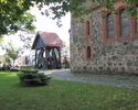 Zdjęcie przedstawia ceglano kamienny kościół oraz dzwonnicę                                                                                                                                             