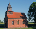 Zdjęcie przedstawia ścianę boczną i front z wejściem kościoła w Suchej.                                                                                                                                 