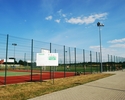 Zdjęcie przedstawia wejście na teren kompleksu boisk sportowych wraz z tablicą informacyjną.                                                                                                            