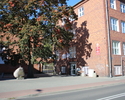 Na zdjęciu widać wejście główne do szkoły oraz znajdujący się przed szkołą pomnik.                                                                                                                      