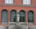 Zdjęcie przedstawia górną część bramy głównego wejścia wraz z ornamentem i rzeźbą.                                                                                                                      