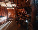 Widok na wnętrze chaty stylizowanej na chatę wikingów, na zdjęciu widoczna jest kobieta wytwarzająca przedmioty domowego użytku z filcu                                                                 