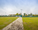 Zdjęcie przedstawia zielone tereny Kompleksu Sportowego Orlik w Bobolicach, w oddali znajduje się boisko.                                                                                               
