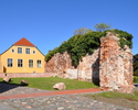 Zdjęcie przedstawia zachowany fragment średniowiecznych murów miejskich oraz pałac w Wolinie                                                                                                            