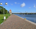 Zdjęcie przedstawia promenadę i cieśninę Dziwna w Wolinie. W tle widać most zwodzony i spichlerz.                                                                                                       
