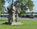Zdjęcie przedstawia plenerową rzeźbę na trawniku przy promenadzie                                                                                                                                       
