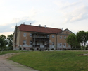 Zdjęcie przedstawia budynek z kompleksu folwarcznego w Gogolicach. Na pierwszym planie widać fragment podwórza gospodarczego, dalej pałac.                                                              