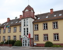 Na zdjeciu widać budynek Urzędu Miasta i Gminy jego wejście główne oraz proporce z flagami Polski i Miasta.                                                                                             