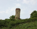 Zdjęcie przedstawia wieżę widokową w Cedyni. Na pierwszym planie widać wzgórze, na którym znajduje się zabytek, na jego szczycie obiekt                                                                 